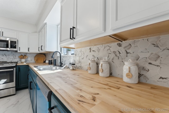 kitchen featuring stainless steel appliances, blue cabinets, butcher block countertops, and a sink