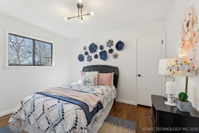 bedroom with a textured ceiling, baseboards, and wood finished floors