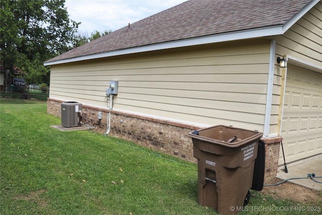 view of side of property with brick siding, a shingled roof, central AC, and a yard