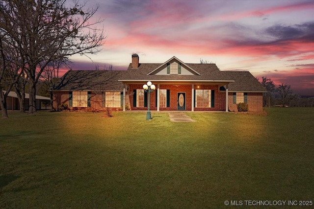 view of front of property featuring a porch, a front yard, brick siding, and a chimney