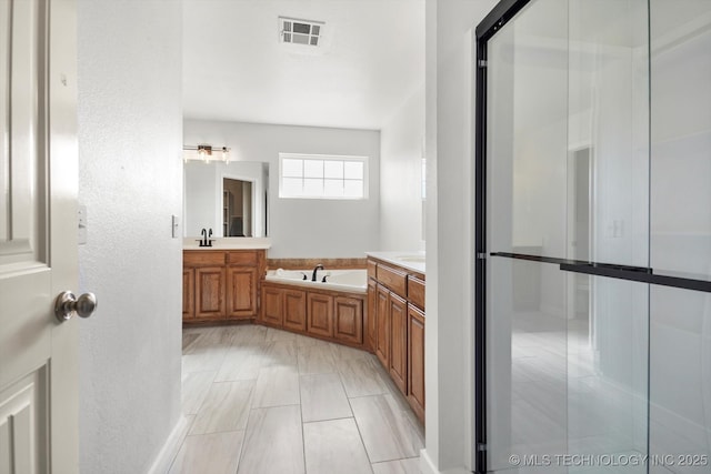 bathroom with visible vents, a textured wall, vanity, and a bath