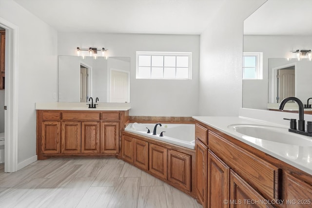 bathroom with a bath, two vanities, a sink, and a wealth of natural light