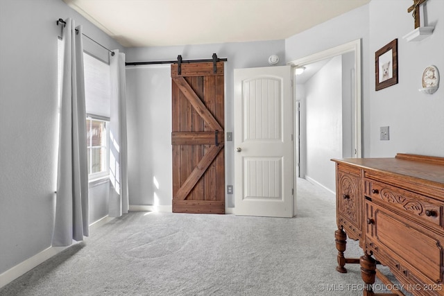 bedroom with carpet flooring, baseboards, and a barn door