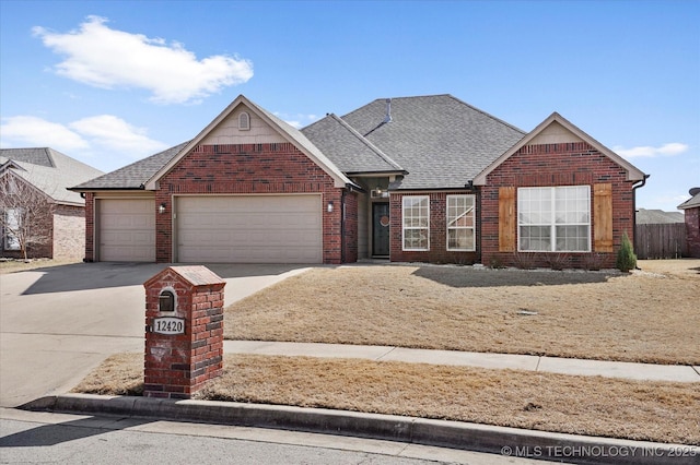 traditional-style house with concrete driveway, brick siding, roof with shingles, and an attached garage