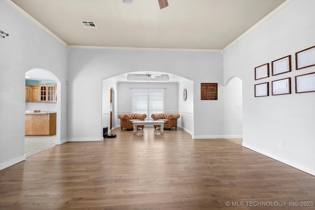 sitting room with arched walkways, visible vents, ceiling fan, and wood finished floors