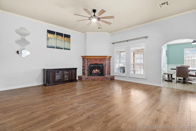 living room featuring ceiling fan, visible vents, arched walkways, and wood finished floors