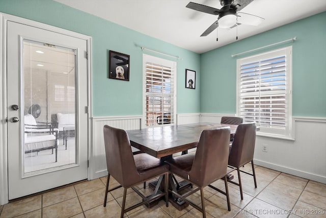 dining room with a wainscoted wall, ceiling fan, and light tile patterned floors