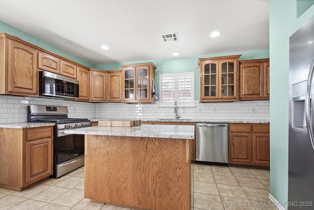 kitchen with stainless steel appliances, brown cabinets, visible vents, and light tile patterned floors