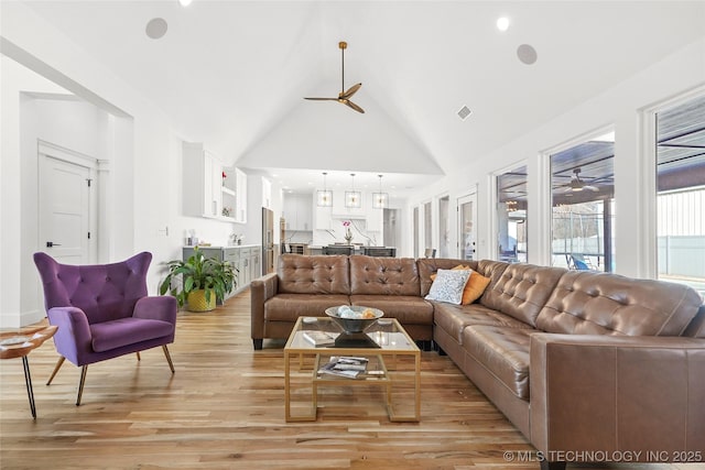 living area with a ceiling fan, high vaulted ceiling, and light wood finished floors