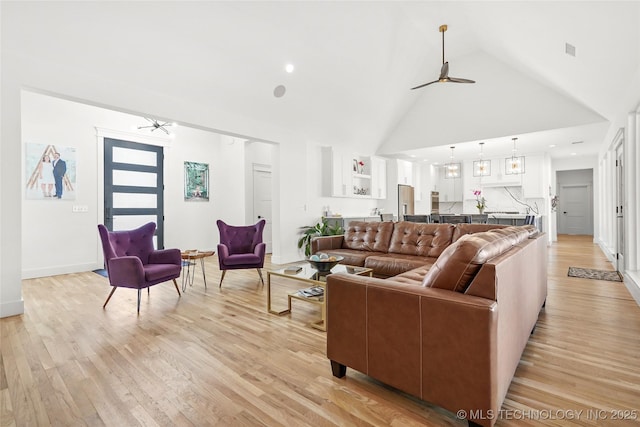 living area with light wood finished floors, visible vents, ceiling fan, high vaulted ceiling, and baseboards