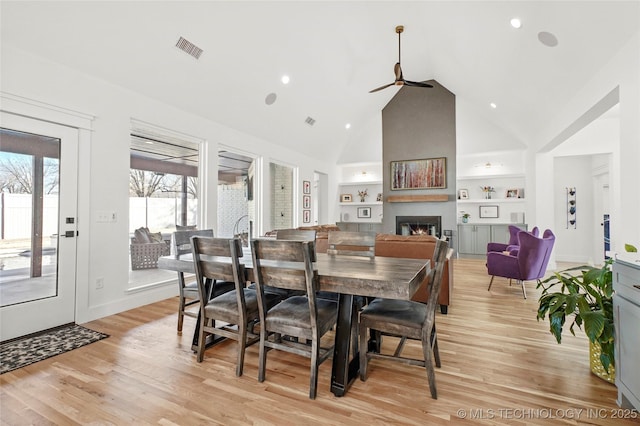 dining area featuring built in features, light wood-type flooring, visible vents, and a fireplace