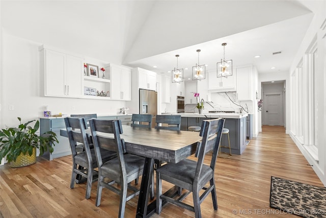 dining area with light wood-style floors, visible vents, high vaulted ceiling, and recessed lighting