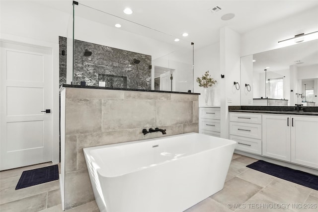 bathroom with tile walls, visible vents, a freestanding bath, vanity, and walk in shower