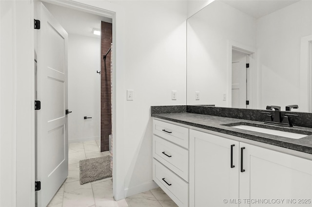 bathroom with marble finish floor, baseboards, walk in shower, and vanity