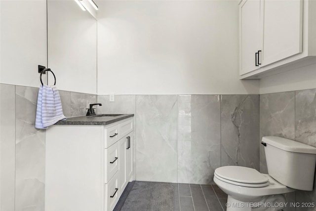 bathroom with tile walls, vanity, and toilet