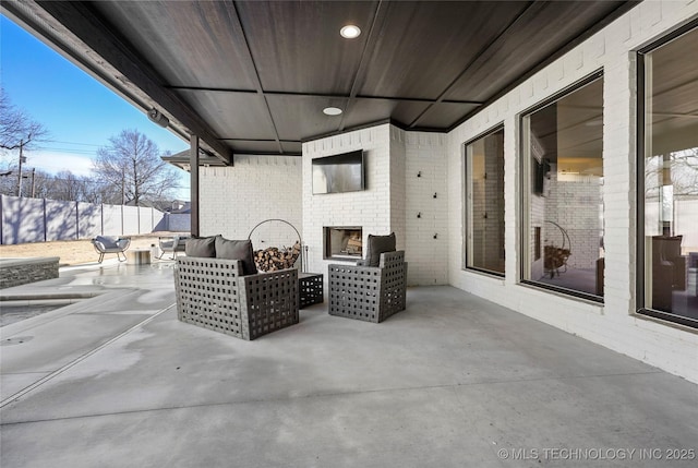 view of patio / terrace featuring fence and an outdoor living space with a fireplace