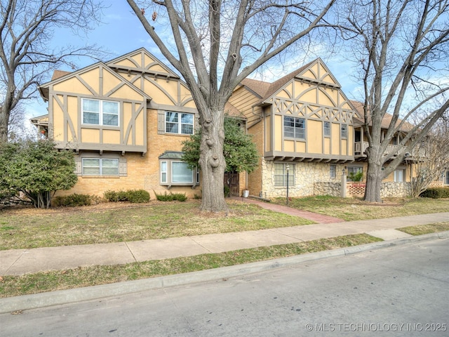 view of front of home featuring brick siding, a front lawn, and stucco siding