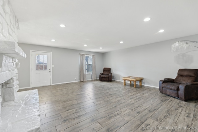 sitting room with a stone fireplace, light wood finished floors, a wealth of natural light, and recessed lighting