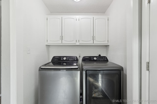 laundry room with cabinet space, a textured ceiling, and separate washer and dryer