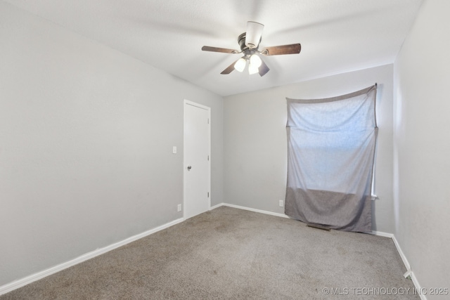 carpeted spare room featuring ceiling fan and baseboards