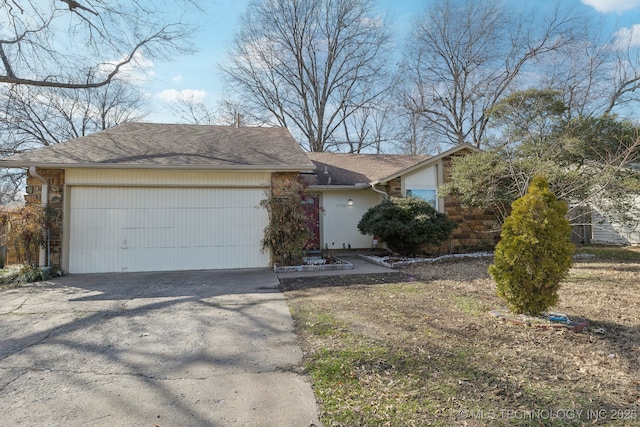 view of front facade with driveway, stone siding, roof with shingles, and an attached garage