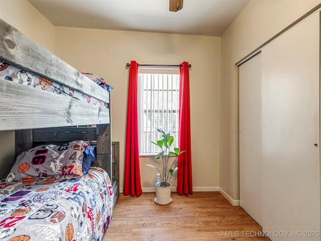 bedroom featuring ceiling fan, baseboards, and wood finished floors