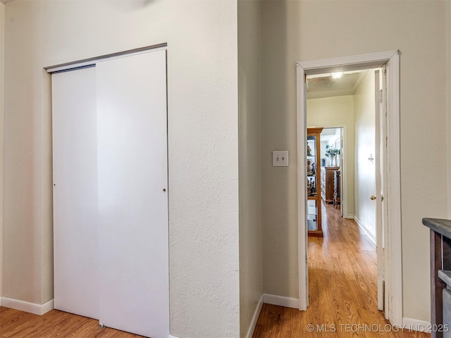 corridor with light wood-style floors and baseboards