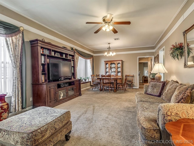 living area featuring crown molding, ceiling fan with notable chandelier, visible vents, and light colored carpet