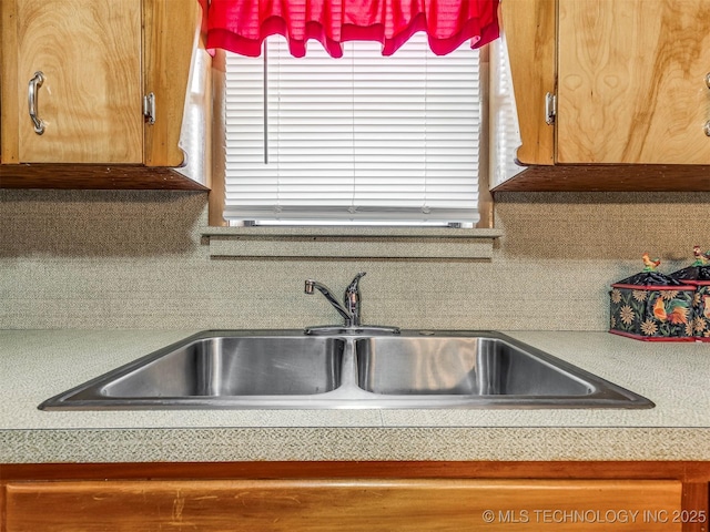 kitchen with light countertops, backsplash, a sink, and a healthy amount of sunlight