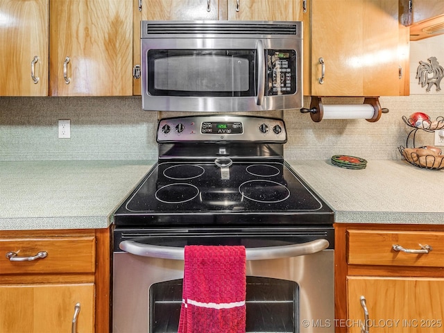 kitchen with brown cabinetry, tasteful backsplash, stainless steel appliances, and light countertops