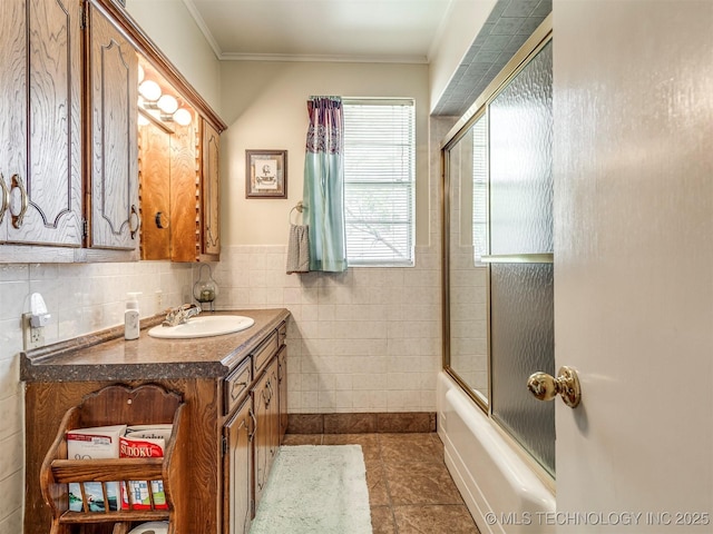 full bath featuring crown molding, tile walls, combined bath / shower with glass door, vanity, and tile patterned floors