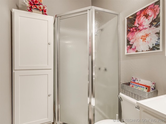 bathroom with a textured wall, a stall shower, and toilet