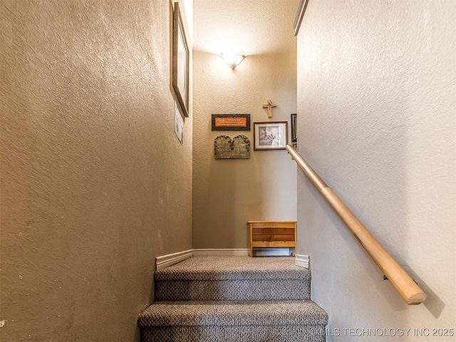 staircase featuring a textured wall and baseboards