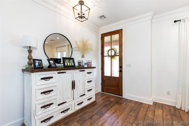 foyer entrance with dark wood-style floors, ornamental molding, visible vents, and baseboards