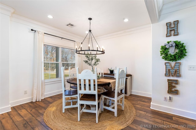 dining room with dark wood-style flooring, crown molding, visible vents, a chandelier, and baseboards