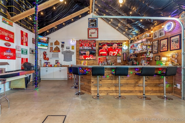 bar with finished concrete flooring, high vaulted ceiling, and a bar