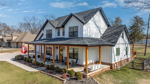 modern farmhouse featuring driveway, covered porch, fence, board and batten siding, and a front yard