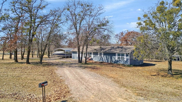 view of front of home featuring dirt driveway and a detached carport