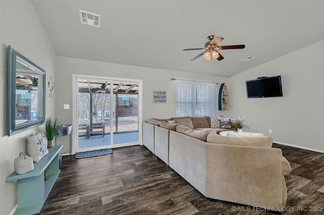 living area with a wealth of natural light, lofted ceiling, dark wood-style flooring, and visible vents