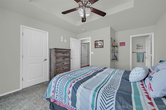 carpeted bedroom featuring baseboards, a raised ceiling, and a ceiling fan