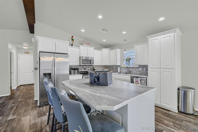 kitchen featuring white cabinets, decorative backsplash, lofted ceiling with beams, a center island, and stainless steel appliances