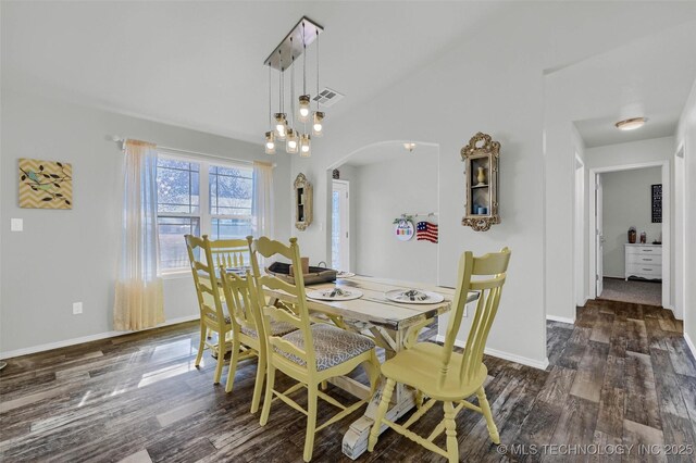 dining space with arched walkways, vaulted ceiling, wood finished floors, and baseboards