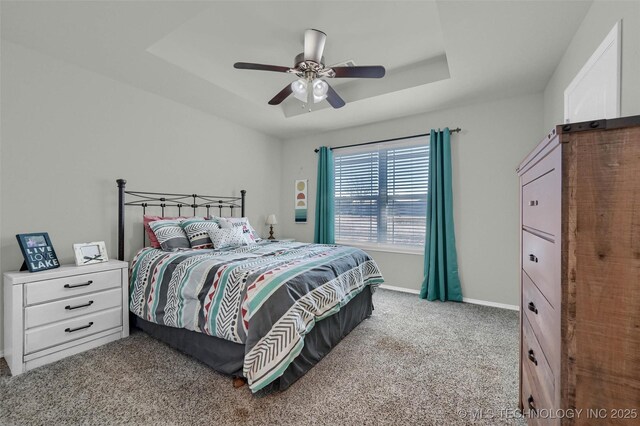 bedroom featuring ceiling fan, carpet floors, a raised ceiling, and baseboards