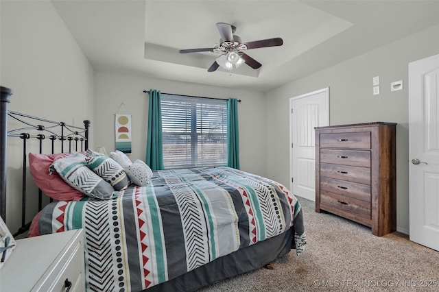 bedroom with ceiling fan, a raised ceiling, and light colored carpet