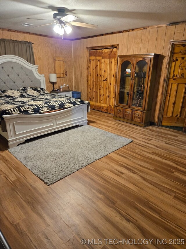 16100 Ash Rd, Morris, OK 74445 - bedroom featuring a textured ceiling, ceiling fan, wooden walls, and wood finished floors
