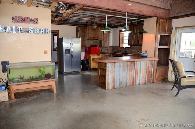 kitchen with a peninsula, stainless steel refrigerator with ice dispenser, a wealth of natural light, and decorative light fixtures