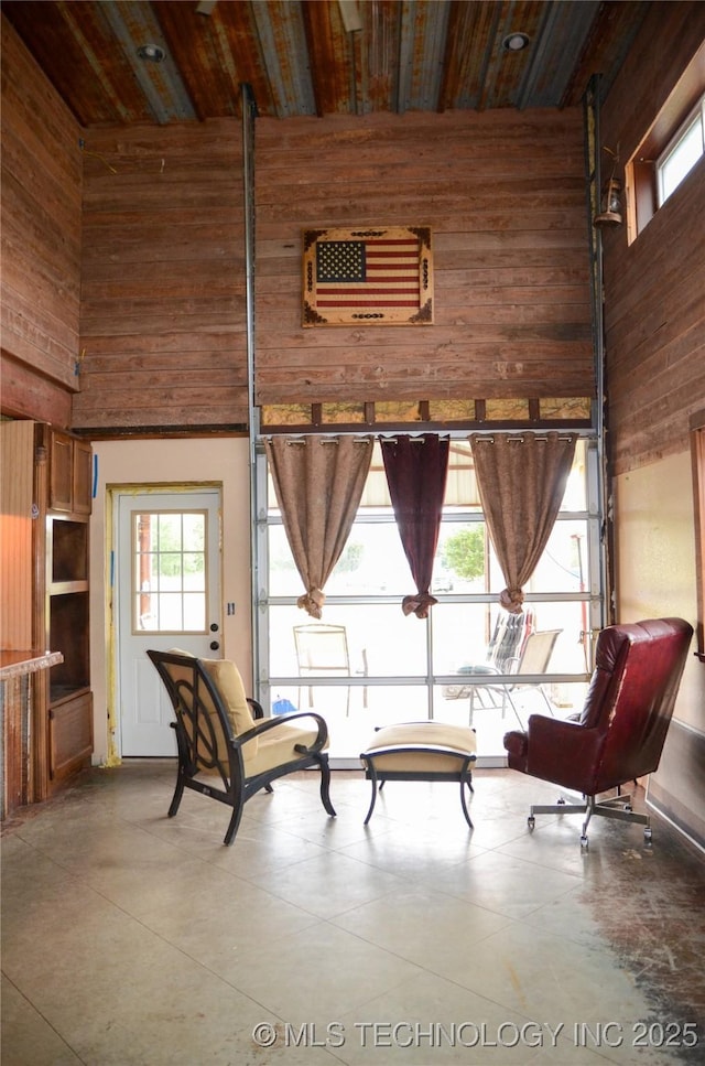 living area featuring a towering ceiling and wood walls