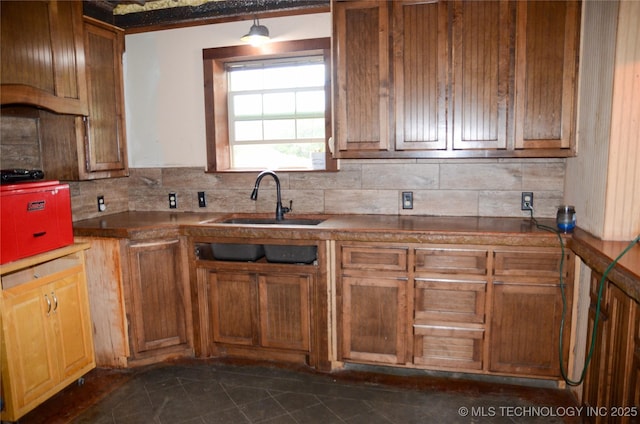 kitchen with dark countertops, brown cabinets, a sink, and decorative backsplash