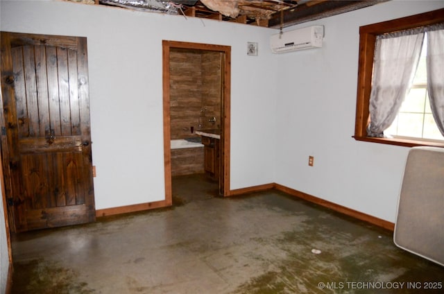 unfurnished bedroom featuring concrete flooring, an AC wall unit, and baseboards