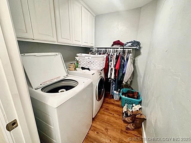 laundry room featuring independent washer and dryer, wood finished floors, and cabinet space